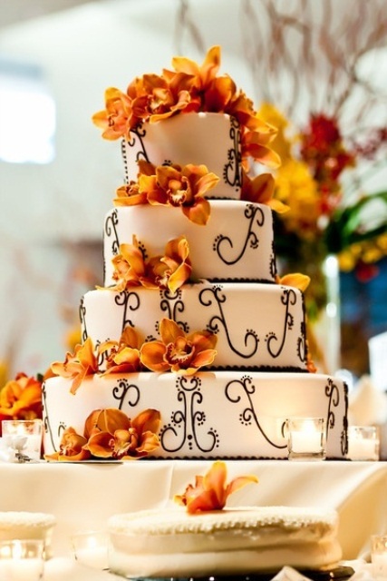 a white wedding cake with chocolate patterns and bold orange blooms for decor