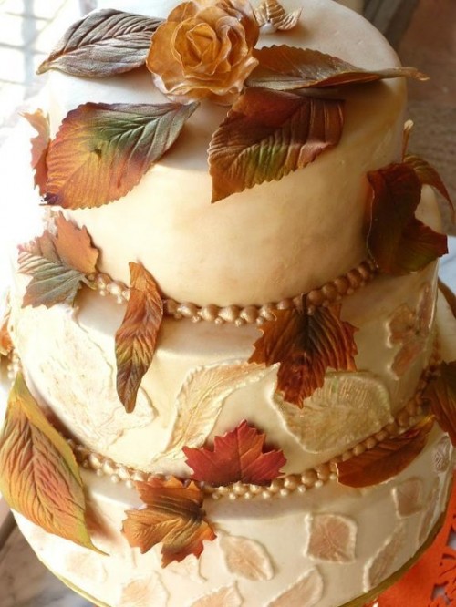 a white textural wedding cake topped with sugar fall leaves and blooms for a chic look