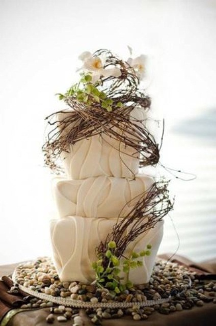 a textural neutral wedding cake decorated with vine and greenery looks unique and bold