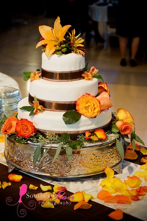 a creative fall wedding cake decorated with chocolate ribbons, bright fall blooms and berries