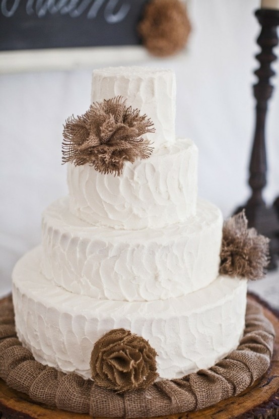 A white textural buttercream wedding cake decorated with burlap balls is ideal for a rustic fall wedding