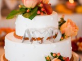 a white patterned fall wedding cake topped with fresh fall blooms and berries and monograms will always work