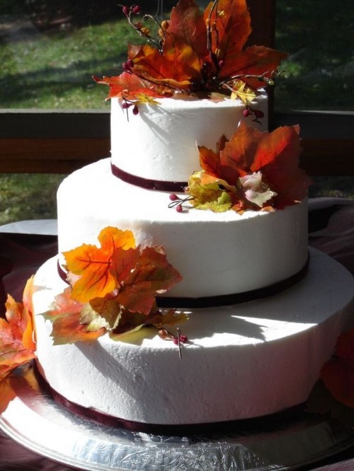 a white fall wedding cake topped with fall leaves and berries is a gorgeous idea with a natural touch
