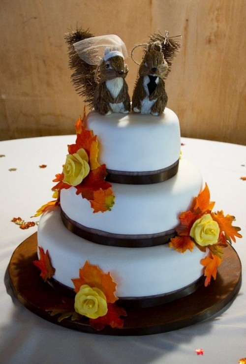 a fall wedding cake with brown ribbons, fall leaves and funny squirrel toppers