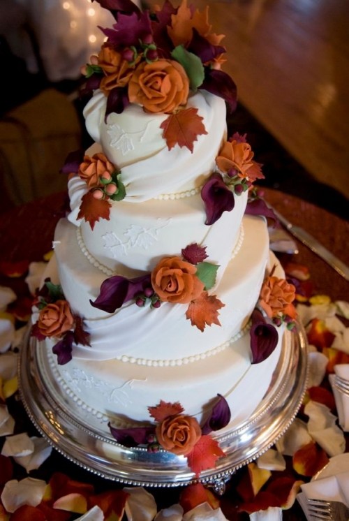 a white wedding cake with sugar beads and ribbons and bright sugar blooms and leaves
