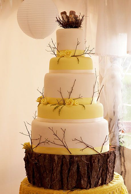 a yellow and white fall wedding cake decorated with twigs and yellow blooms plus a nest with branches