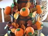 a creative fall wedding cake showing off wooden baskets filled with leaves and sugar pumpkins