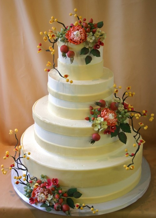 a striped neutral fall wedding cake decorated with sugar blooms, leaves and berries