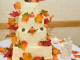 a patterned square and round wedding cake with fall leaves and pumpkins and a fun pumpkin topper