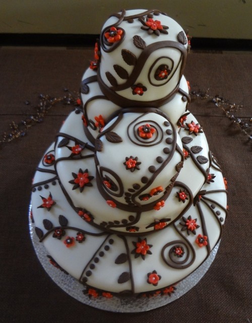 a unique buttercream wedding cake decorated with chocolate and orange patterns all over looks very bold