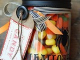 a jar with colorful Halloween candies with a striped strap and tags is a stylish and fun Halloween wedding favor