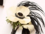 a white bloom boutonniere with black feathers and greenery