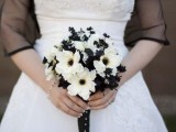 a white wedding dress, a black sheer coverup and a black and white wedding bouquet