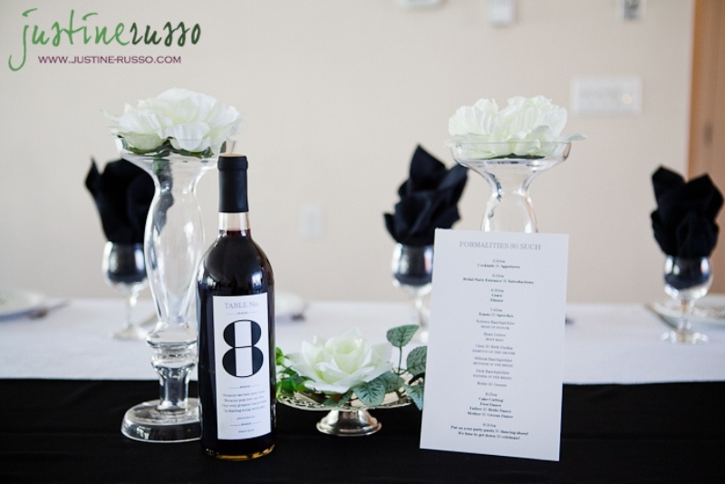 Clear glass vases with white blooms, white table runners and napkins plus a table number