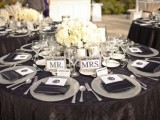 a black, white and silver wedding tablescape with a lush floral centerpiece