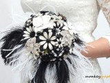 a brooch, feather and paper flower wedding boquet with black and white feathers