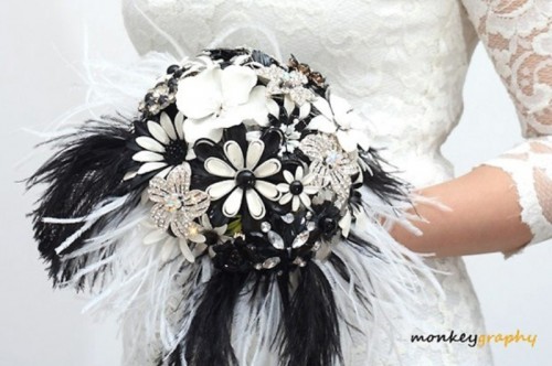 a brooch, feather and paper flower wedding boquet with black and white feathers