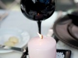 a black candle holder and black glasses plus blush candles and white pearls