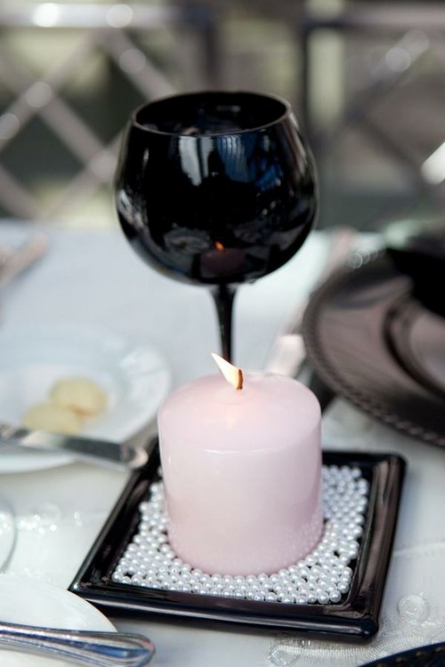 a black candle holder and black glasses plus blush candles and white pearls