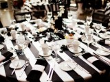 a stylish black and white wedding tablescape with a striped tablecloth, black and white napkins and a centerpiece