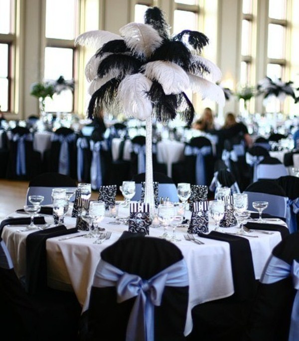 A chic black and white table setting with a tablecloth, runners, napkins and a feather centerpiece