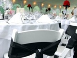 a white tablescape, white chairs and a black bow on the chair