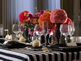 a black and white striped tablecloth, black candle holders with red blooms