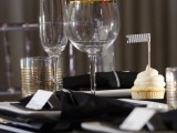 a simple place setting with white chargers, black napkins and gilded touches for more chic