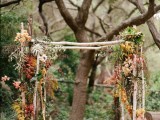a branch wedding arch topped with blooms, air plants and fall leaves for a cool fall wedding