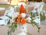 an elegant fall wedding centerpiece in blush, white, orange with foliage and succulents