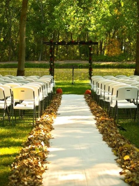 fall leaves lining up the outdoor wedding aisle and a couple of pumpkins in the end
