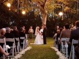 a living tree decorated with lights and vine balls hanging down plus flower petals to line up the aisle