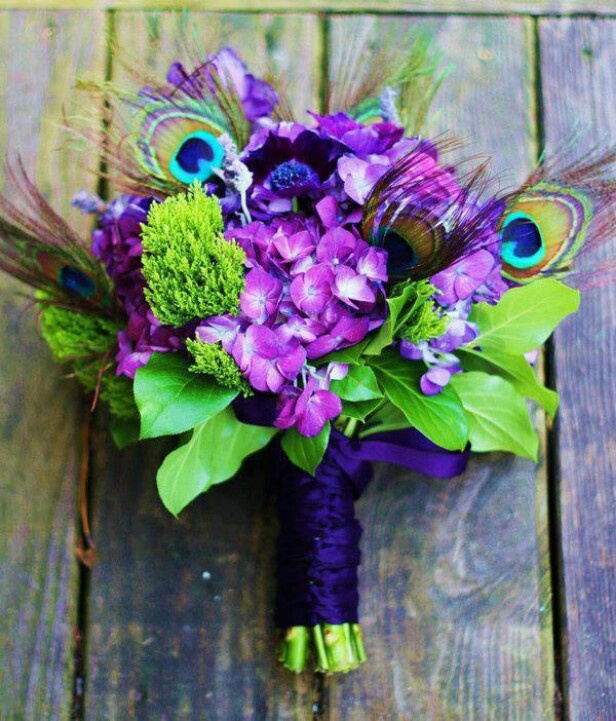 A purple and green wedding bouquet with peacock feathers and a purple wrap