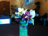 a turquoise wedding centerpiece with purple touches and peacock feathers