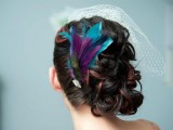 a bright wedding hairpiece of turquoise, purple and peacock feathers plus a cage veil on the other side
