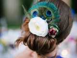 a low bun accented with fresh blooms and a peacock feather for a creative look