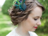 a wavy low updo highlighted with a single peacock feather is a very fun and whimsy idea