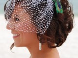a birdcage veil with a vintage brooch and a peacock feather attached