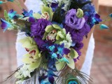 a bold cascading wedding bouquet done with green, purple and blue blooms and peacock feathers