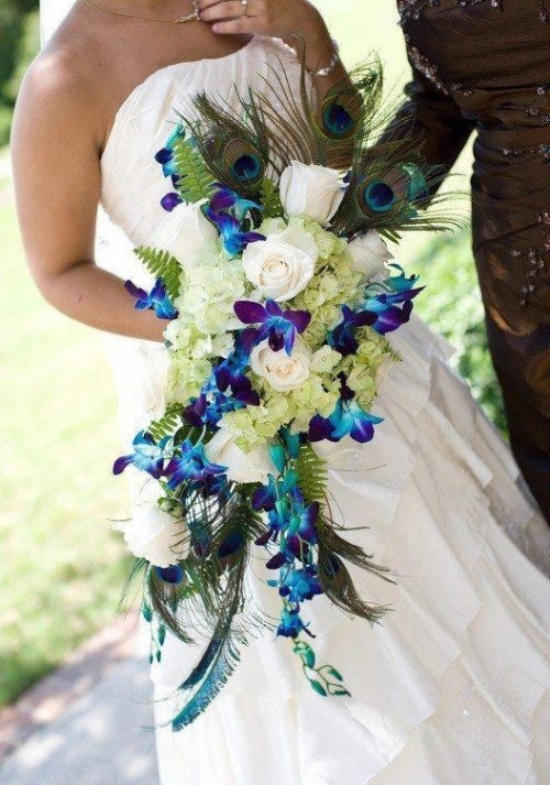 a bold cascading wedding bouquet of purple orchids, white hydrangeas and peacock feathers