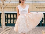 a romantic wedding dress with a white cowl neck bodice and a blush ruffle skirt plus a blush silk sash