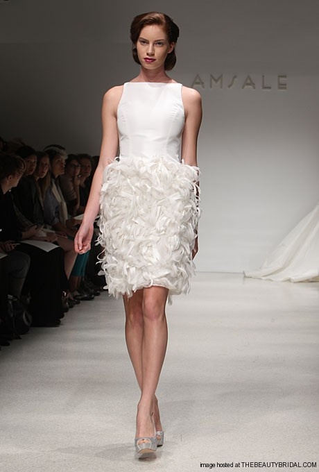 a short wedding dress with a sleeveless plain bodice with a high neckline and a feather skirt is very glam