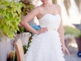 a strapless A-line wedding dress with a draped bodice and a ruffle multi-layer skirt with a sash for a vintage-inspired look