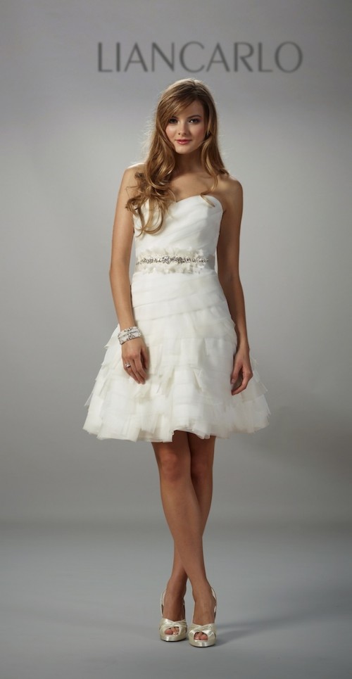 a strapless short draped and tiered wedding dress with an embellished sash for a playful and fun look