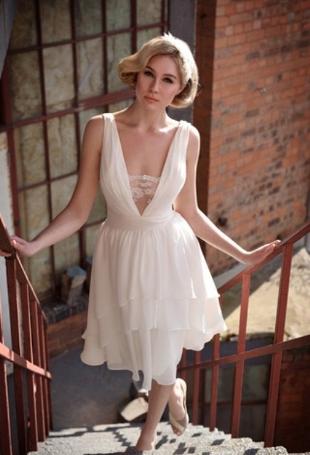 a romantic and sexy vintage-inspired draped A-line wedding dress with no sleeves and a plunging neckline covered with lace plus a tiered skirt