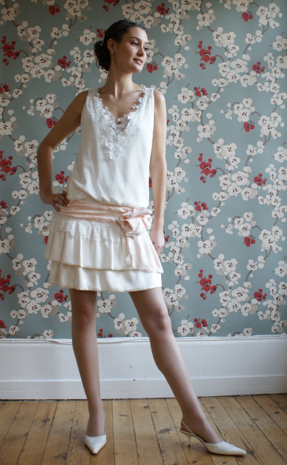 A vintage inspired wedding dress   a plain with lace one, with a ruffle skirt, a lace applique neckline and a pink sash