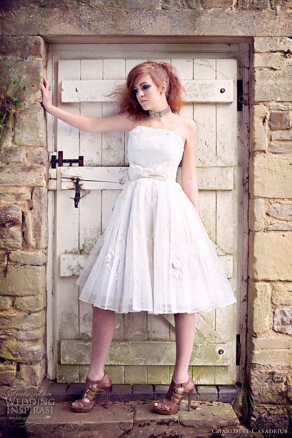 A white vintage inspired A line wedding dress with a pleated skirt, lace appliques and a large bow