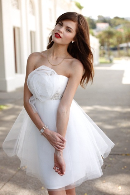 a strapless A-line wedding dress with a tulle flower and a layer over the dress and an embellished sash looks playful and catchy