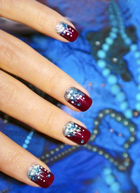 burgundy nails with silver snowflakes, blue and silver stars and snoflakes and a bit of glitter