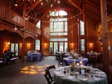 a barn wedding venue with string lights, chandeliers and sconces for a cozy and intimate atmosphere in the space
